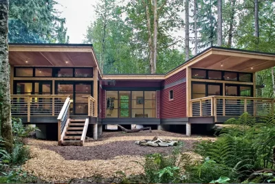 Vista exterior de casa prefabricada moderna en bosque con diseño sostenible y amplios ventanales